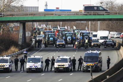 Agentes de policía vigilan decenas de tractores que participan en una manifestación en la autopista A15 cerca de Argenteuil, al norte de París, Francia, este lunes 29 de enero de 2024.