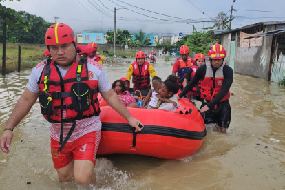 Los bomberos rescatan en una boya a un grupo familiar que estaba atrapado en su casa por la inundación.