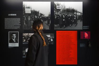 Una mujer junto a una fotografía impresa de Missak Manouchian (I), en la exposición "Los extranjeros en la resistencia en Francia", en del Museo de la Shoáh, en París