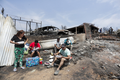 Personas del campamento irregular “Pompeya” almuerzan entre los escombros, tras los incendios del día viernes 2 de febrero, en la zona de Viña del Mar.