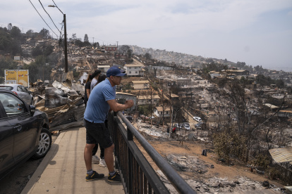 Personas observan hoy viviendas destruidas en el sector de Achupallas, afectado por incendios forestales de Viña del Mar, Región de Valparaiso (Chile). El número de fallecidos en los devastadores incendios que azotan la región de Valparaíso, a 100 kilómetros al oeste de Santiago, aumentó a 99, de los cuales solo 32 han podido ser identificados, informó este domingo el Servicio Médico Legal (SML) de Chile. EFE/ Adriana Thomasa