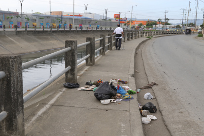 Varios ciudadanos colocan fundas con desechos junto a un canal entre las ciudadelas Las Orquídeas y Los Vergeles.