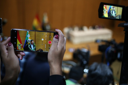 Una mujer graba con un teléfono al presidente de Bolivia Luis Arce durante la promulgación de la ley para elecciones judiciales este 6 de febrero de 2024, en la "Casa Grande" en La Paz (Bolivia).