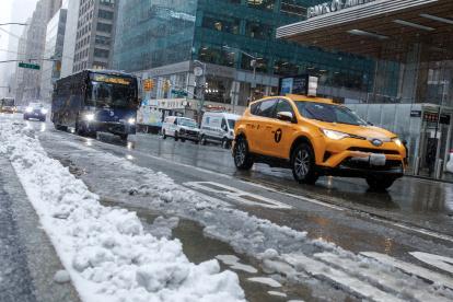 Nueva York. Varios vehículos circulan por la Sexta Avenida mientras cae nieve.