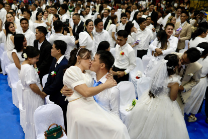La pareja de novios Reynaldo Pingol y Maricel se besan durante una boda masiva el día de San Valentín en la ciudad de Bacoor.