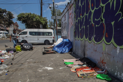 Dos personas que se cubren para, presuntamente, consumir alguna droga permanecen en una calle.