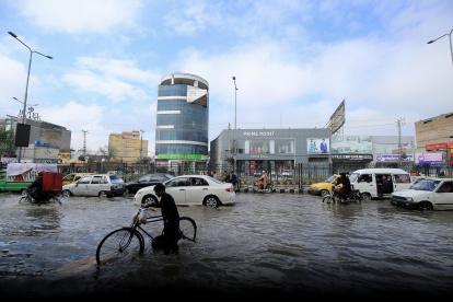 Trabajadores en una calle inundada durante un fuerte aguacero en Peshawar, Pakistán, el 19 de febrero de 2024.