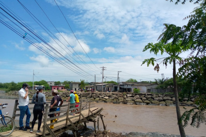 Un grupo de personas observa los restos de un puente de madera que cruzaba sobre el río Atravezado, en Libertador Bolívar, Santa Elena.