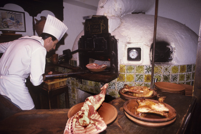 Un cocinero introduce una fuente en el horno de asar.