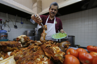 Un hombre cortando trozos de carne para elaborar birria en el comercio Birriería Cocula