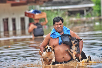 Personas abandonan sus viviendas después que el río Acre aumentara su caudal, este 26 de febrero de 2024 en Cobija en el departamento de Pando (Bolivia).