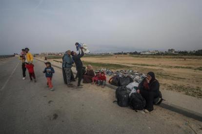 Un grupo de palestinos descansa tras cruzar desde el norte de la Franja de Gaza hacia el sur por la carretera Al Rashid, el 26 de febrero de 2024.