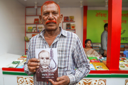 Shahjahan Bhuiyan, con un ejemplar de su libro "Cómo fue la vida del verdugo", en la caseta de la editorial Kingbondonti durante la feria anual del libro en Dacca, Bangladesh.