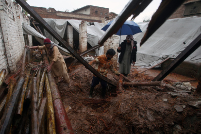 La gente recoge sus pertenencias de su casa que se derrumbó tras un fuerte aguacero en Peshawar, Pakistán,
