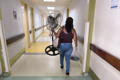 Una mujer lleva un ventilador a la sala donde está internado su paciente, en el hospital Teodoro Maldonado Carbo, del IESS.