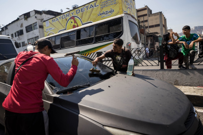Jóvenes limpian vidrios de vehículos en un semáforo, este miércoles en Caracas (Venezuela). Un total de 3.984.517 venezolanos, con edades comprendidas entre los 3 y los 24 años, no cursan ningún tipo de estudios, según la Encuesta de Condiciones de Vida (Encovi) del año 2023.

,