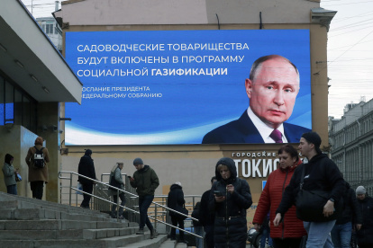 Ciudadanos pasan frente a una gigante pantalla digital con la imagen del presidente Vladimir Putin.