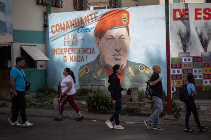Caracas. Varias personas ladean un mural del fallecido Hugo Chávez.