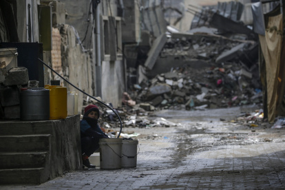 Un niño llena un cubo con agua entre los escombros de estructuras destruidas durante una operación militar israelí en el campo de refugiados de Al Nusairat, en el sur de la Franja de Gaza.