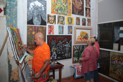 Arte. Jorge Ganín pinta un cuadro en el bar como parte de una muestra de su arte en vivo, mientras visitantes del sitio observan las obras.