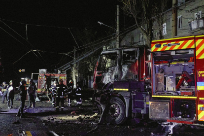 Rescatistas ucranianos trabajan cerca de su vehículo dañado en la escena de un ataque nocturno ruso con drones contra un edificio residencial en Járkov.