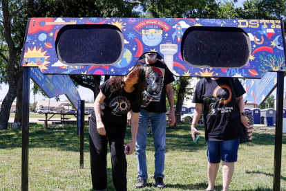 Una familia mira a través de un par de gafas gigantes especiales para el eclipse solar en el Veterans Memorial Park en Dripping Springs, Texas
