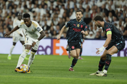 El delantero brasileño del Real Madrid Vinicius Jr. (i) se escapa con el balón de los jugadores de Manchester City