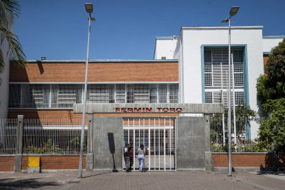 Personas aguardan en la puerta de una unidad educativa pública de una zona popular, en Caracas (Venezuela).