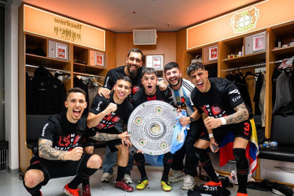 El ecuatoriano Piero Hincapié (d) junto a sus compañeros y el plato de campeón en el vestidor del Bayer Leverkusen.