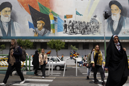Teherán. Mujeres iraníes cubiertas con velo pasan junto a un mural del líder supremo, el ayatolá Ali Jamenei.