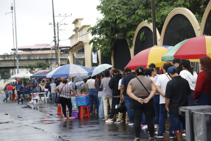 Los electores hacen fila en los exteriores de los recintos electorales cubriéndose de las lluvias con paraguas