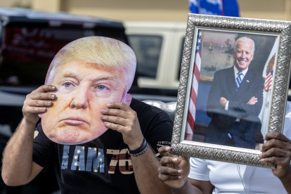 Hecho. Un partidario de Biden sostiene un retrato del presidente junto a un seguidor de Trump que lleva su foto.