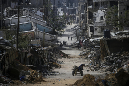 Varios palestinos caminan entre edificios destrozados en Jan Yunis tras un ataque israelí.