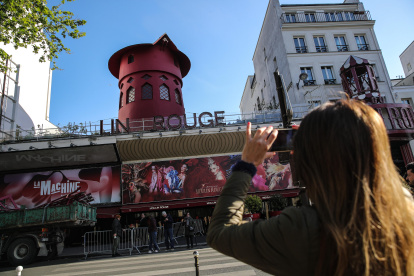 La gente se detiene para tomar fotos de la fachada del Moulin Rouge sin sus alas en París. Durante la noche del 24 al 25 de abril de 2024, las aspas del Moulin Rouge se derrumbaron sin causar víctimas.