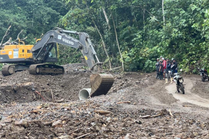 Los vehículos atraviesan con cautela el camino provisional abierto en la carretera afectada por deslaves.