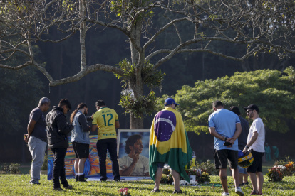 Seguidores del automovilista brasileño Ayrton Senna muestran respeto frente a la tumba del piloto