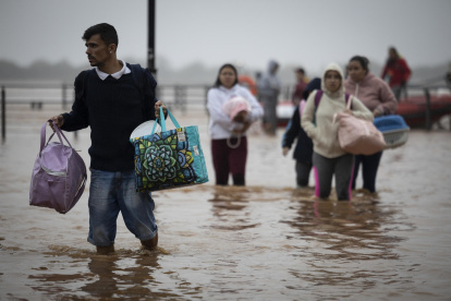 Habitantes de las islas costeras del lago Guaíba caminan entre el agua tras ser rescatados por el Ejército brasileño.