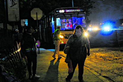 Los pasajeros esperan los buses en una oscuridad tenebrosa.