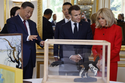 El presidente Xi Jinping (i) y Emmanuel Macron, miran los regalos durante el intercambio de obsequios entre las naciones, en el Palacio Presidencial del Elíseo en París.