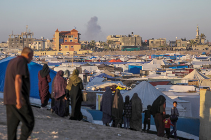 Palestinos desplazados internos en un campamento miran el humo que se eleva al fondo después de un ataque aéreo israelí, en Rafah, en el sur de la Franja de Gaza, el 7 de mayo de 2024.