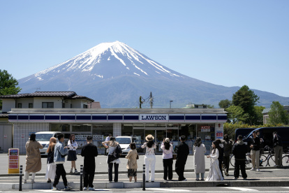 Turistas hacen fotografías de la tienda de la cadena Lawson con el Monte Fuji al fondo, en Fujikawaguchiko, al norte del Monte Fuji, Japón, el 10 de mayo de 2024.
