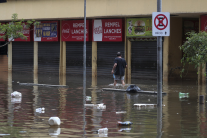 Un hombre camina en una calle inundada de agua y basura en un centro comercial este lunes, en Porto Alegre (Brasil).