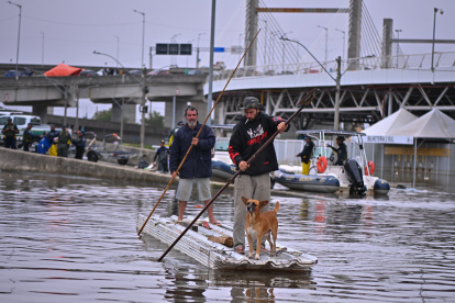 Dos hombres utilizan unas tejas para navegar en una zona inundada el 16 de mayo de 2024, en el municipio de Canoas, estado de Rio Grande do Sul (Brasil).