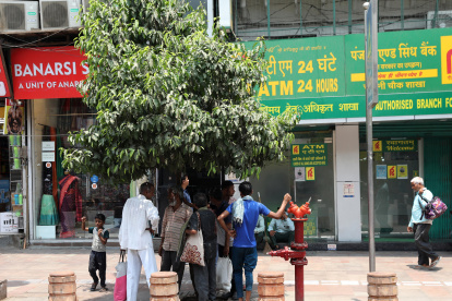 Un grupo personas se paran bajo la sombra de un árbol para evitar la ola de calor en el casco antiguo de Delhi, India, el 22 de mayo de 2024.