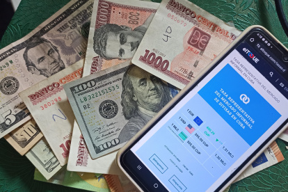 Se muestran billetes junto a un celular con la aplicación del diario digital independiente El Toque,