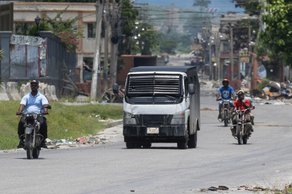 Motociclistas transitan junto a un carro blindado de la Policía Nacional Haitiana, para poder pasar por la zona cercana al Palacio Nacional, donde son habituales los enfrentamientos con las bandas armadas, este sábado, en Puerto Príncipe (Haití). La Policía Nacional Haitiana emitió hoy sus condolencias a la familia de los ciudadanos estadounidenses asesinados por pandilleros y aseguró que identificará y apresará los culpables de los crímenes. EFE/ Orlando Barría