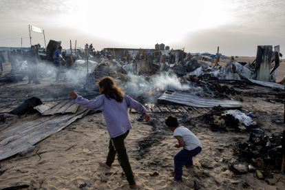 Palestinos entre los daños en un campo de desplazados de Rafah atacado por Israel este 27 de mayo.