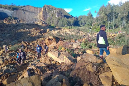 La gente camina con sus pertenencias en la zona donde un deslizamiento de tierra azotó la aldea de Kaokalam, provincia de Enga, Papúa Nueva Guinea, el 24 de mayo de 2024.