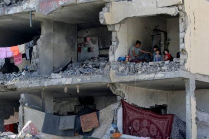 Un hombre palestino y sus hijos en una habitación destruida tras un bombardeo israelí en Rafah