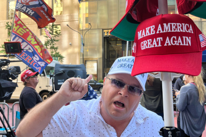 Un seguidor del expresidente Donald Trump grita consignas frente a una cámara mientras sostiene una gorra de "Haz a los Estados Unidos grande otra vez" en Nueva York.